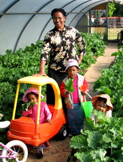 Sister Jean in the Greenhouse with the children eating raw greens